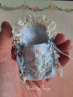 someone holding an ornament in their hand with lace and flowers on the inside