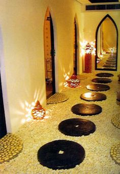 a long hallway with lots of decorative items on the floor and lit up by candles