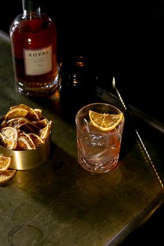 a bottle of kova is sitting next to some orange slices and a glass on a metal tray