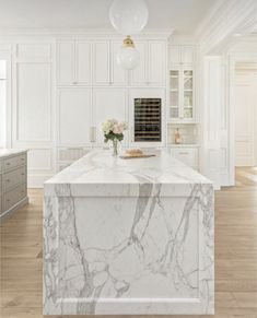 a kitchen with marble counter tops and white cabinetry, along with an island in the middle