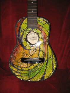 a colorful guitar is sitting on a red velvet surface, with the frecks painted all over it