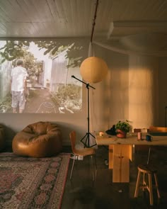 a living room with a large screen and chairs