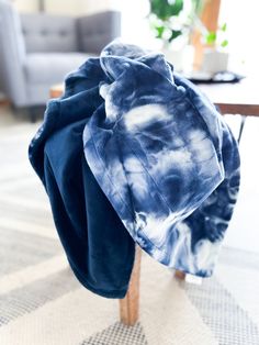 a blue and white tie - dyed hat sitting on top of a wooden chair next to a table