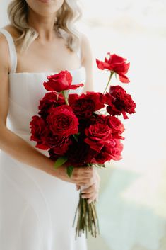 a woman holding a bouquet of red roses