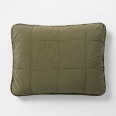 an olive green pillow on a white wall with a square pattern in the middle and one side