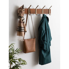 a coat rack with two coats hanging from it's sides and a purse on the other side