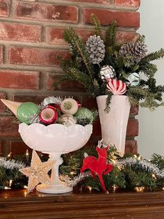 a christmas mantle with pine cones, ornaments and other holiday decorations on it in front of a brick wall