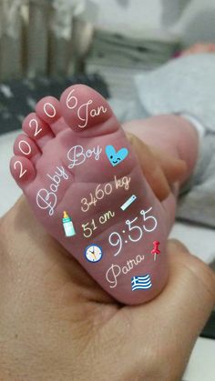 a hand holding a baby's birth stone with the date written on it in different languages