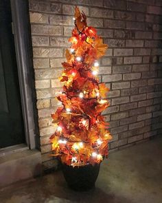 a potted plant that has some lights on it and is decorated with autumn leaves