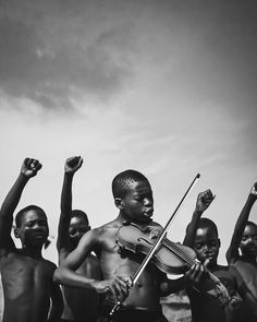 a group of young boys standing next to each other holding up their arms and violin