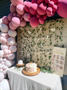 a table topped with a cake next to balloons and a sign that says, we hope you are one