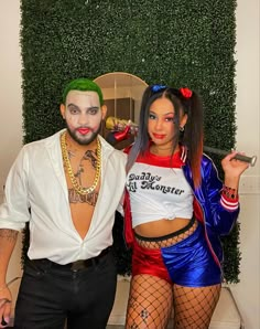 a man and woman dressed in costumes posing for the camera with green wall behind them