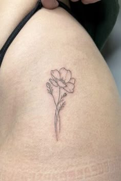 a woman's thigh with a small flower tattoo on the back of her thighs