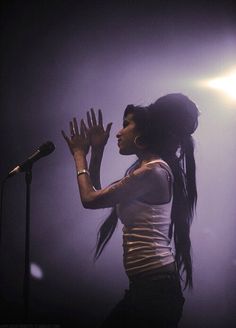 a woman with long hair standing in front of a microphone