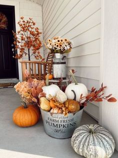 pumpkins and gourds are sitting on the front porch for fall decorating