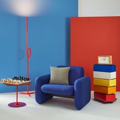 a blue chair sitting next to a table with chess pieces on it and a clock