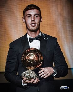 a man in a tuxedo holding a ballon d'or award on stage