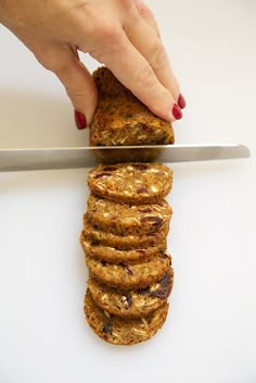 a person is cutting up some cookies on a white surface with a knife in front of them