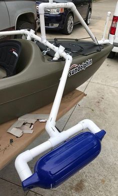 a blue and white boat sitting on top of a wooden table next to a parked car