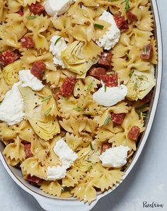 a casserole dish filled with pasta, meat and cheese on a white surface