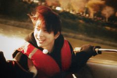 a young man wearing a life jacket smiles while sitting in a boat on the water