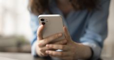 a close up of a person holding an iphone in their hands and looking at the screen