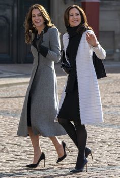 the two women are walking down the street together, one is wearing a gray coat and black