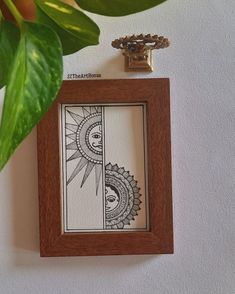 a wooden frame hanging on the wall next to a potted plant and a key