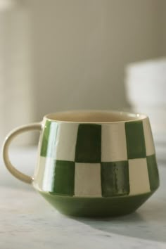 a green and white checkered coffee cup sitting on a counter