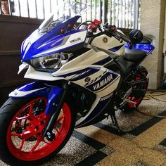 a yamaha motorcycle is parked in front of a building with red and blue rims