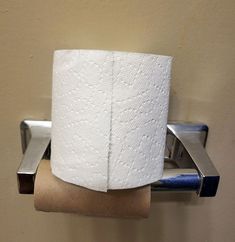 a roll of toilet paper sitting on top of a metal holder next to a wall