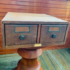 an old wooden table with two drawers on it