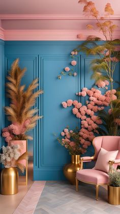 a room with blue walls, pink chairs and gold vases filled with flowers on the floor