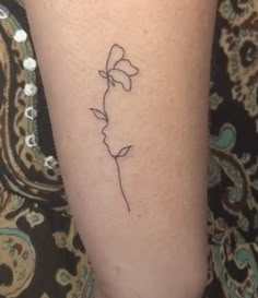 a woman's leg with a small flower tattoo on the left side of her arm