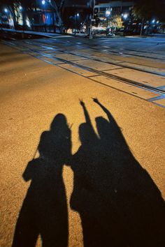 the shadow of two people standing next to each other with their hands in the air