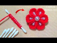 two crocheted flowers are next to each other on a table with knitting needles