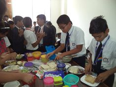 some people are standing around a table with food on it