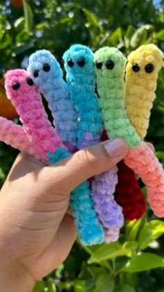 four crocheted worms are held in the palm of someone's hand