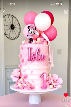 a minnie mouse cake with balloons and the number one on it for a first birthday