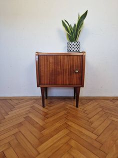 a wooden cabinet with a potted plant sitting on it's top shelf next to a white wall