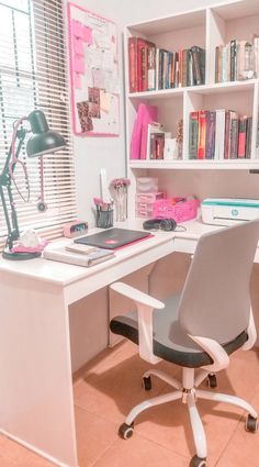 a white desk topped with a laptop computer next to a book shelf filled with books