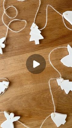 some white ornaments are hanging on a wooden table