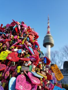 a large pile of colorful luggage tags in front of a building with a television tower in the background