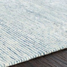 a close up view of a rug on a wooden floor with blue and white stripes