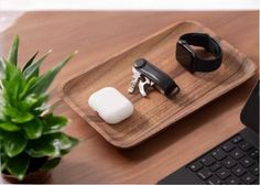 a wooden tray topped with two different items on top of a desk next to a keyboard