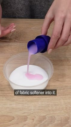 someone is pouring something into a bowl with pink liquid in it on a wooden table