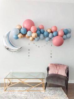 balloons and stars are hanging on the wall above a chair in a room with a rug