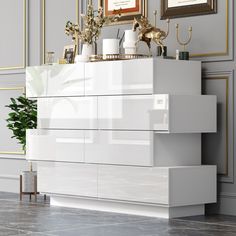 a large white dresser sitting in a living room next to a painting on the wall