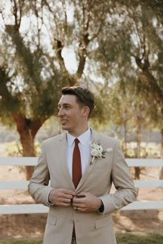 a man in a tan suit and red tie