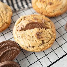 chocolate chip cookies cooling on a rack with one cookie broken in half and the other partially eaten